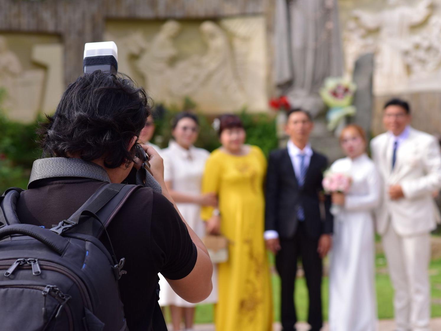A photographer with an external flash photographing a group at an event — stock photograph